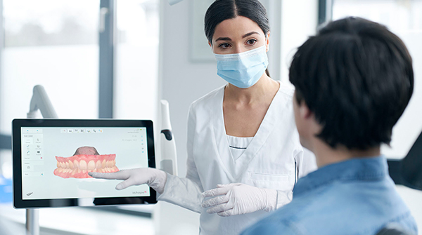 Dentist using CAD/CAM dental equipment and technology to educate a patient