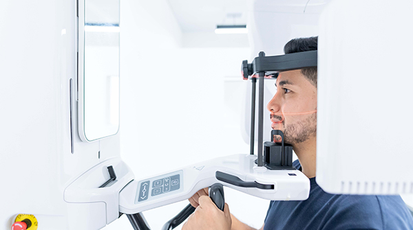 dental patient positioned in a CBCT machine that is taking a digital radiograph of his mouth